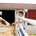Chloe Chavez standing with a cow outside a barn