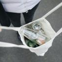 A person holding a canvas bag with glass bottles in it
