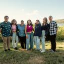 A group poses on a lake shore
