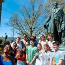 A group of students take a photo in front of the Ezra Cornell statue on the Arts Quad. 