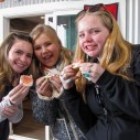 three woman stand together eating orange slices