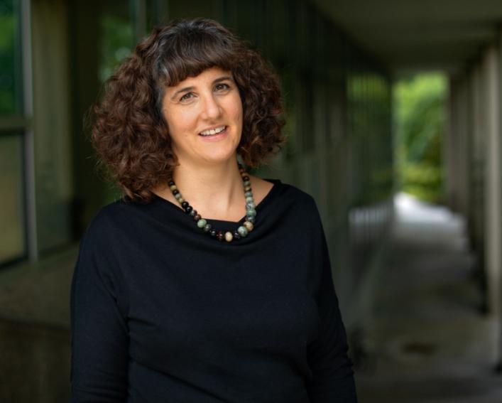 Female professor stands in outdoor archway 