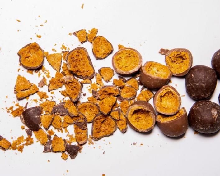Chocolate covered chickpeas crushed up on a white table 