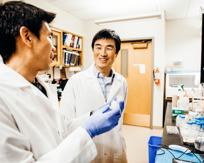 assistant professor working in his lab with postdoctoral researcher