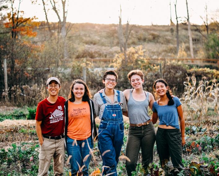 Student farm managers pose in field of vegetables