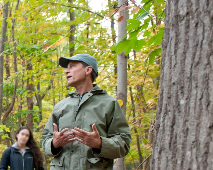 Andrew Zepp stands in front of a tree and speaks to a crowd