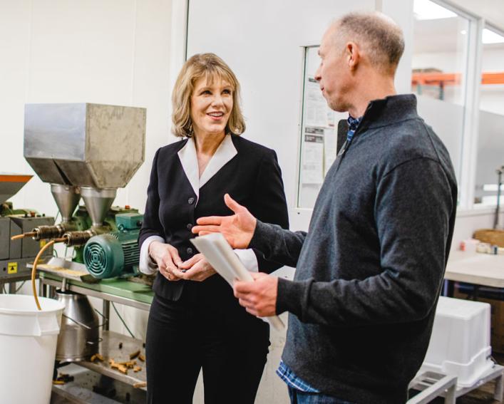 A woman and a man stand outside a room where nuts are being pressed into nut butter