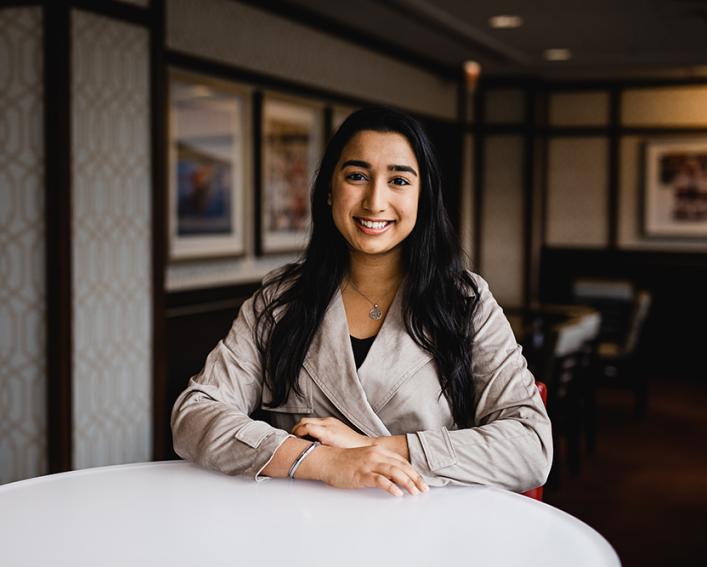 A student sitting at a table with her arms folded in front of her. 