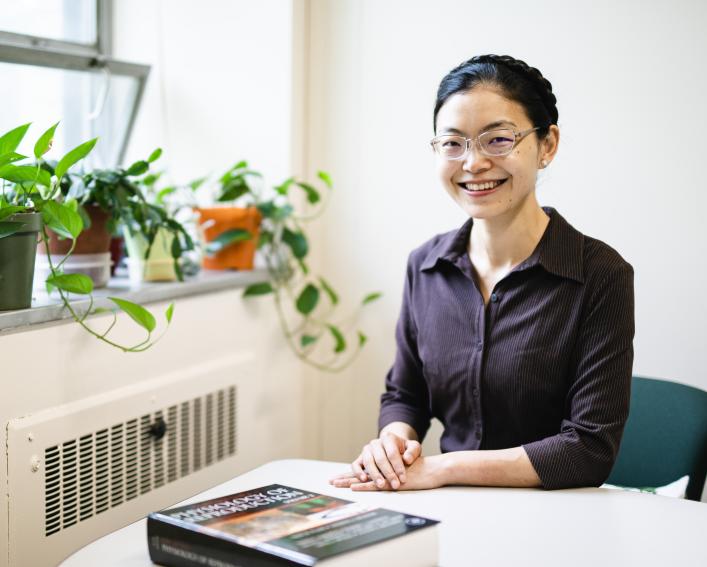 A woman sits at a table and smiles