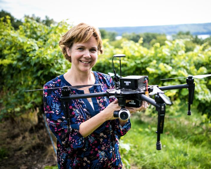 women holds drone while stnading in a vinyard