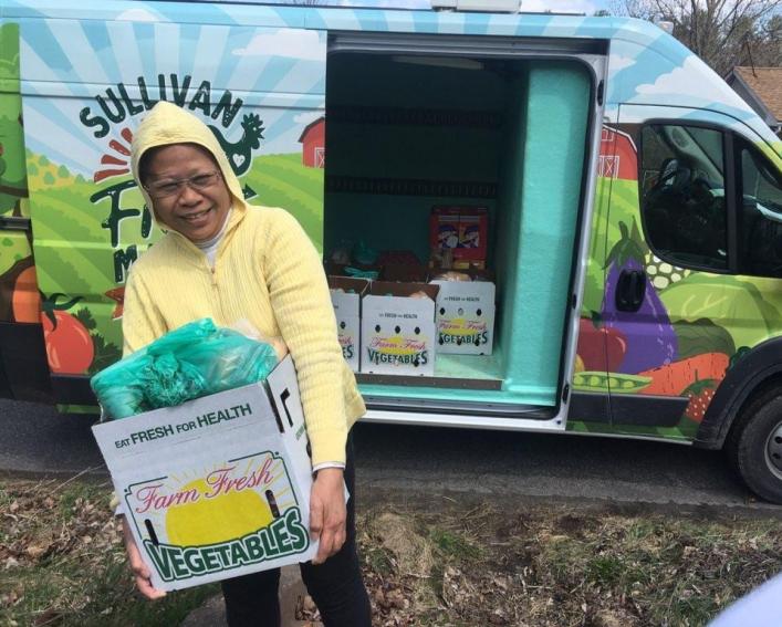 a woman carries a box of food from a van