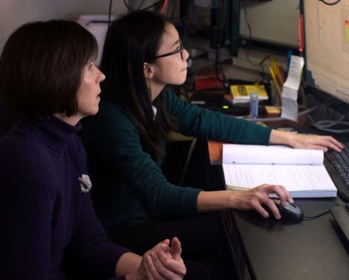 two women examining a computer image of plant leaves