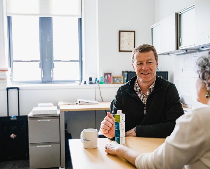 Two people speaking at a desk with blocks on it