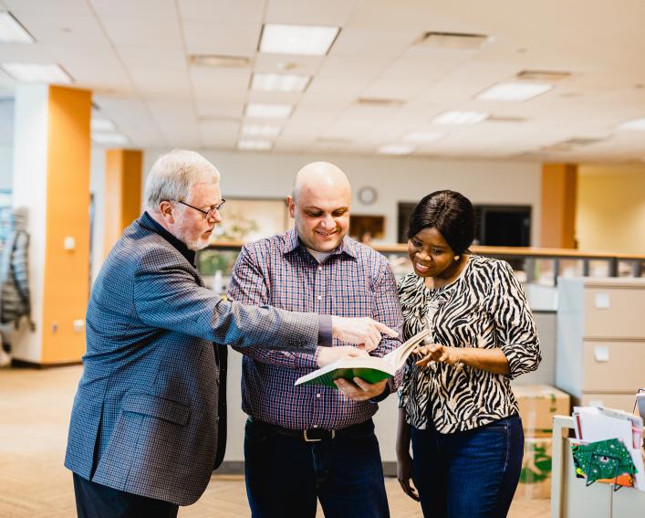 Three people looking at a page of a textbook