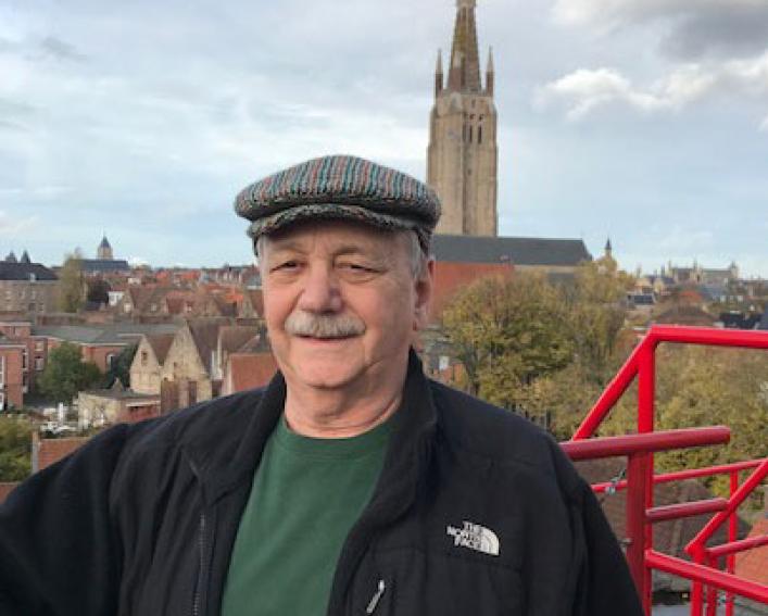 A man stands on a balcony overlooking a city