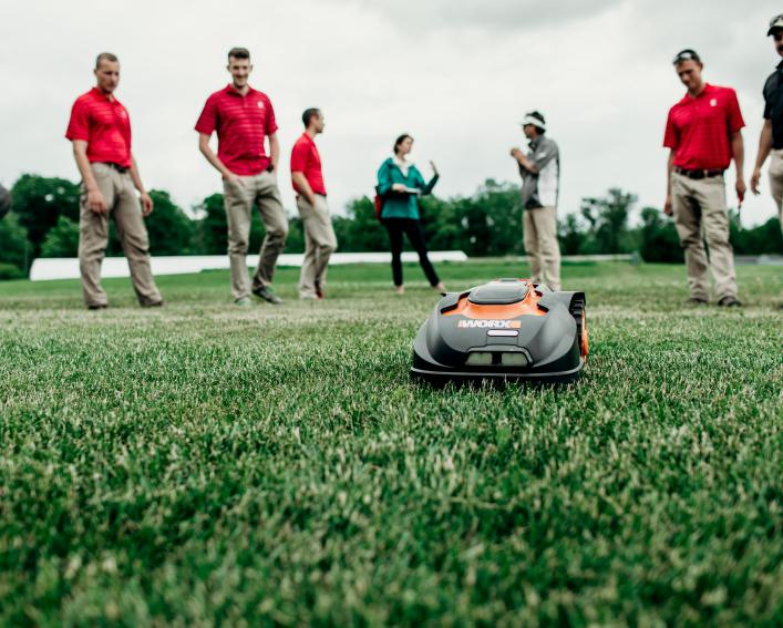 group watching robotic mower