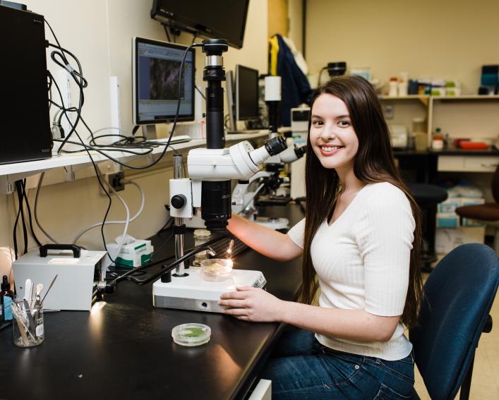 woman seated beside a microscope