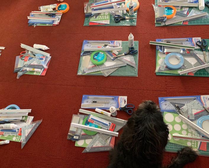Piles of supplies, including pens, pencils and rulers, laid out on the floor.