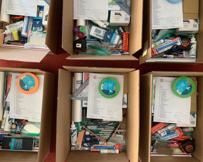 Cardboard boxes of supplies, including pencils, pens, charcoal sticks, erasers, engineering and architectural scales, drafting triangles, X-Acto knifes, cutting mats, sketchbooks and materials like paper, clay and cardboard.