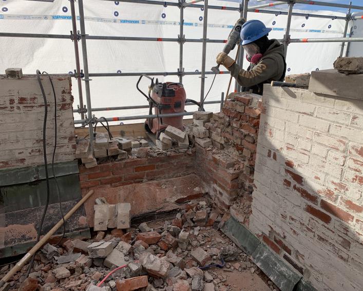 worker dismantles the cornice masonry
