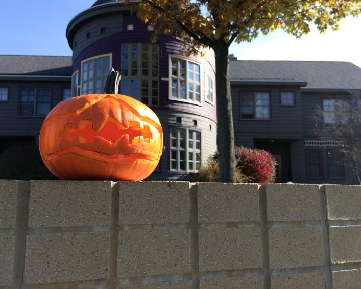A pumpkin sits on a stone wall in front of the Akwe:kon program house.