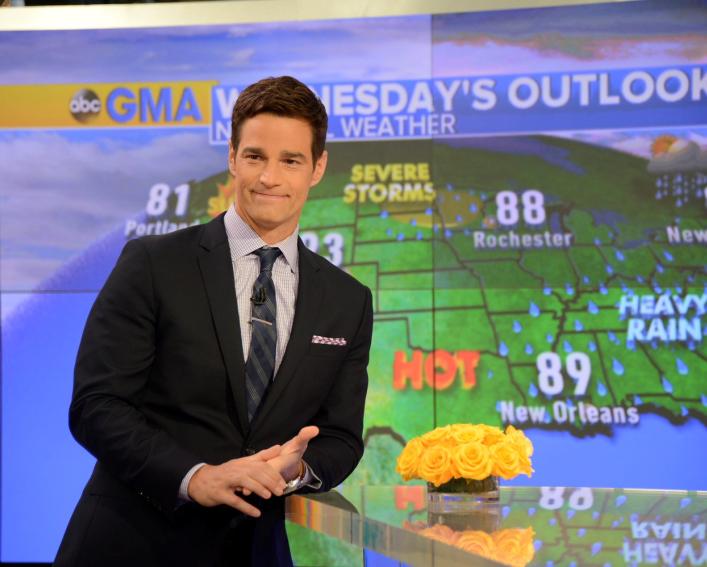 Weatherman stands in front of a weather screen