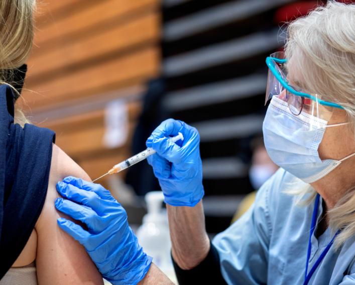 A person giving another person a vaccination indoors