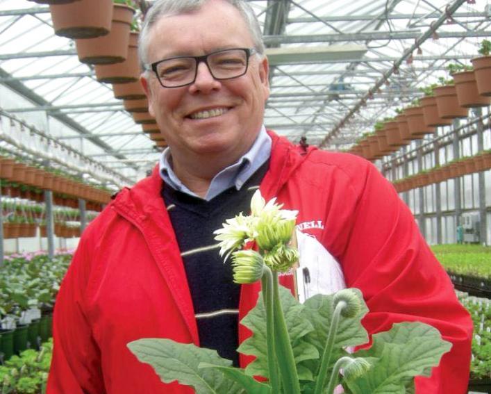 mark bridgen with flowering plant in greenhouse