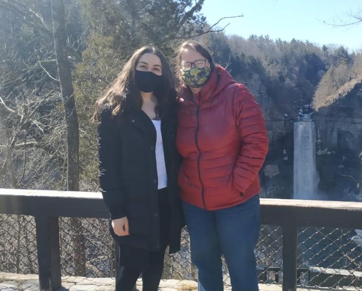 Two individuals pose in front of a waterfall 