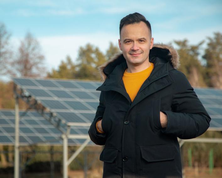 Dmytro Zinkevych stands in front of solar panels