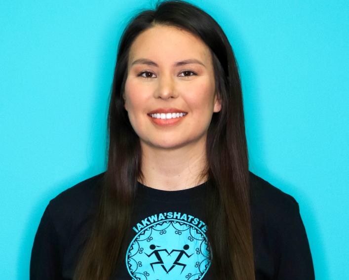Photo of a woman smiling with long dark hair waring a dark colored long sleeve shirt.