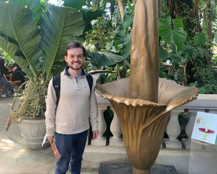 Stephen Stresow '22 standing with a golden titan arum statue. 