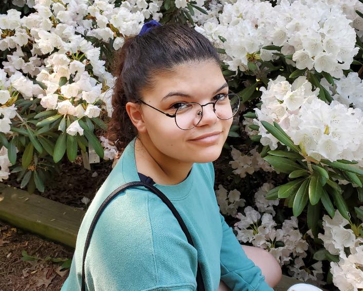 Jenna Webb '22 sitting outside with white flowers