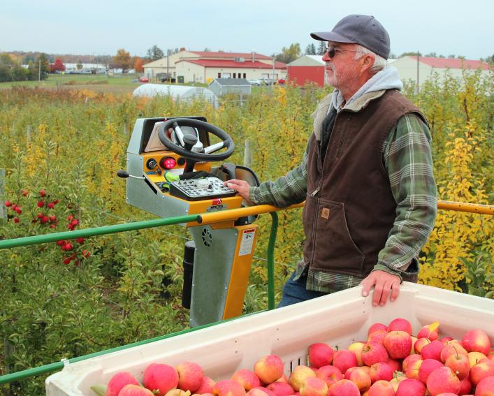A researcher moves a container of apples on a tractor.