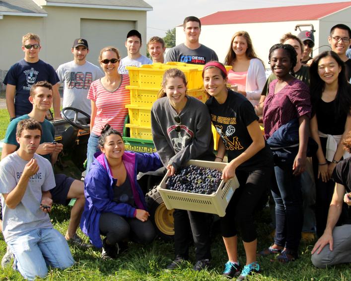 A group of student pose for a photo holding a container of grapes.