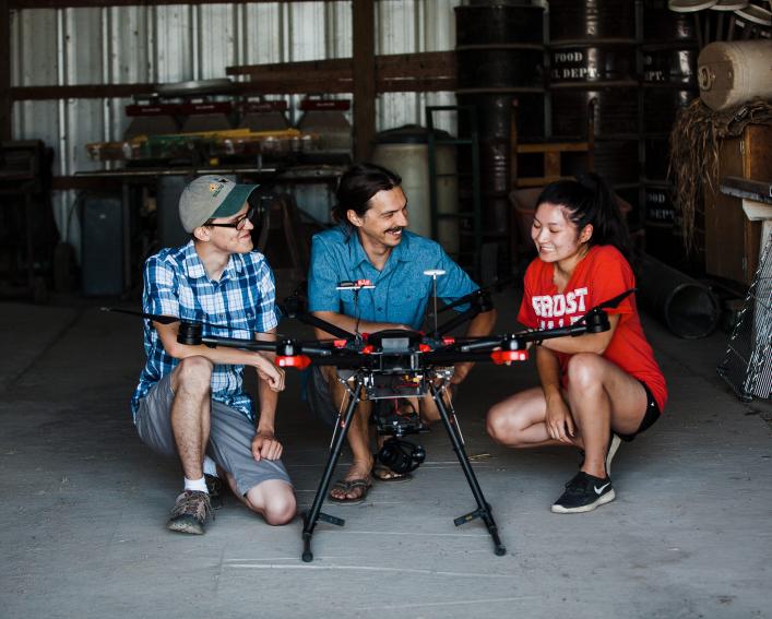 Students and technician prepare a drone for info gathering flight.