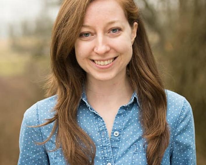 Headshot photograph of a woman wearing a blue denim shirt with long light brown hair.