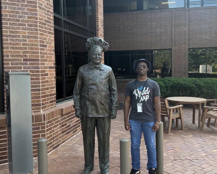 Albert Charles standing next to a statue 