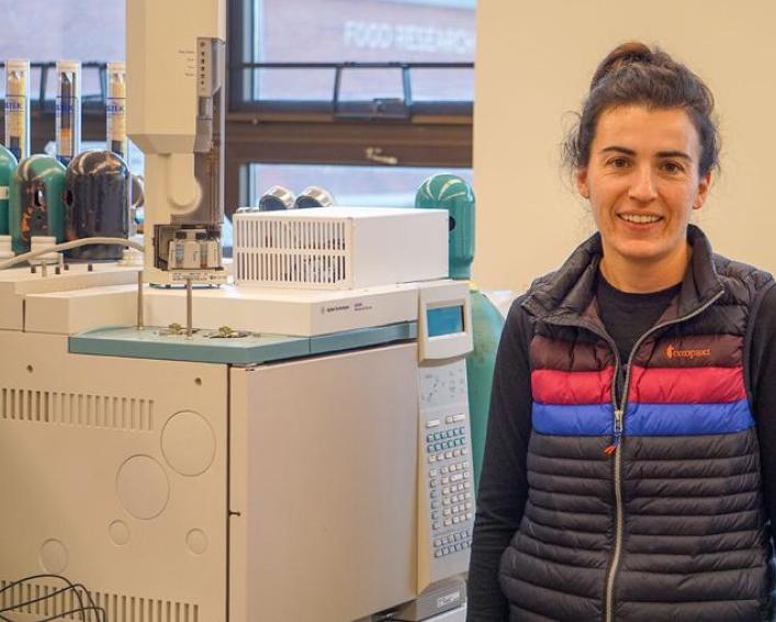 A woman stands in front of large lab equipment