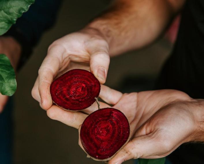 A pair of hands holding a beet cut in half