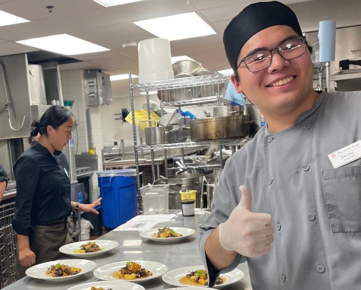 student giving a thumbs up in front of food