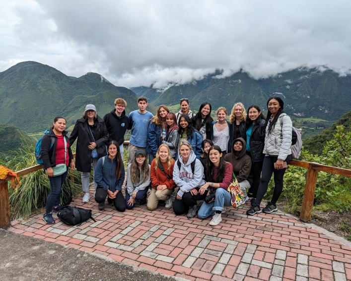 Students pose for group photo in front of volcano