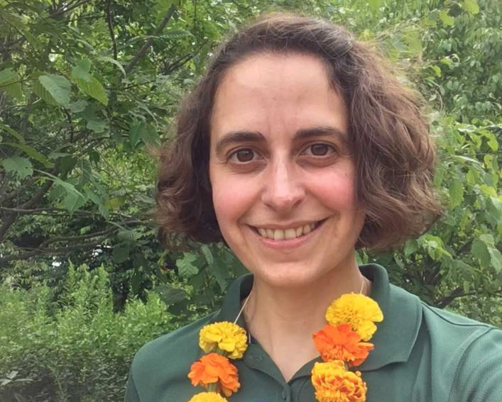 Smiling person with a necklace made of orange and yellow flowers