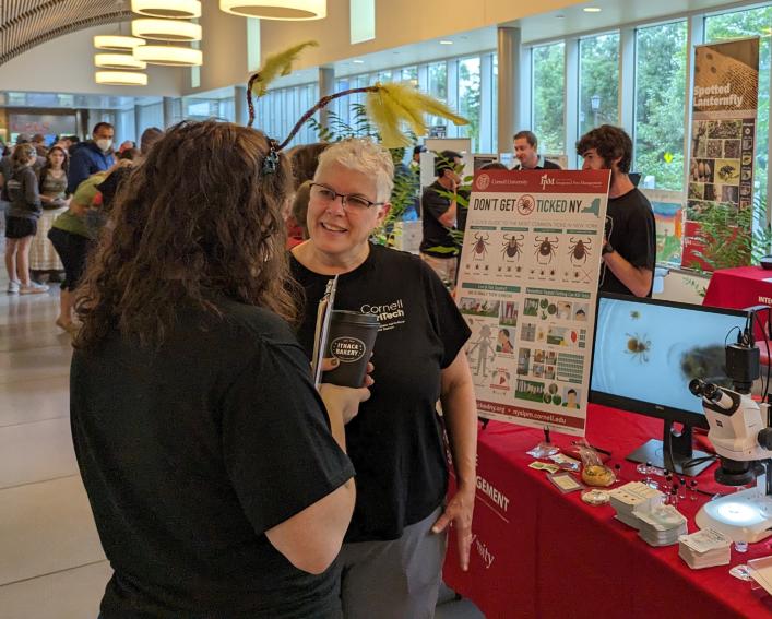 people having a conversation in front of an information table about ticks and spotted lanternflies