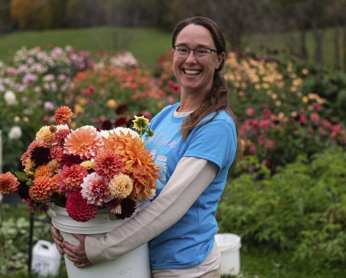 Smiling person holding a bucket full of flowers