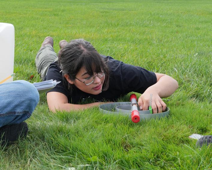 A student laying on the grass while conducting an experiement