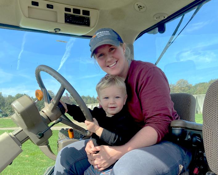 a woman and child sit in a tractor cab
