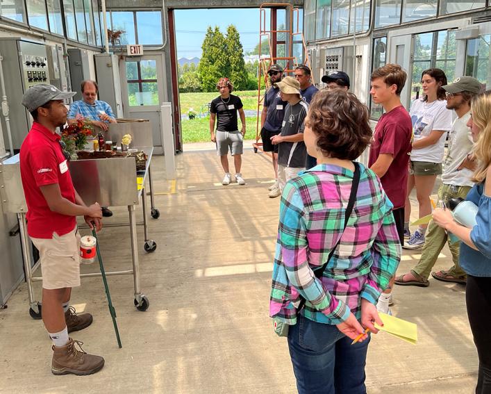 Person speaking to a group of people in a greenhouse