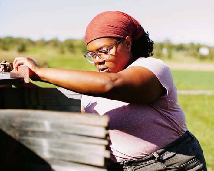 Person in a red hair scarf using weeding equipment