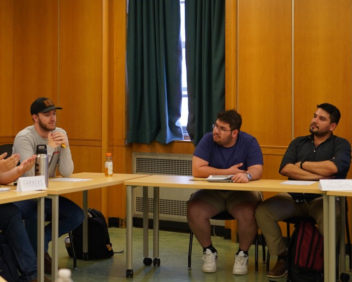 Four people sit at two different tables, the one on the left is labeled "farmers" and the one on the right is labeled "crop consultants."